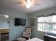 Bright bedroom featuring a ceiling fan, TV, cozy chair, and a window with a view to the outside at 12931 W Florida Dr, Lakewood, CO 80228