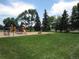 Community playground with a slide, swing and green grass at 12931 W Florida Dr, Lakewood, CO 80228