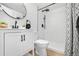Modern bathroom with white marble-style shower, wood-look floors, black fixtures, and patterned shower curtain at 5116 Jellison St, Arvada, CO 80002