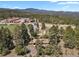 Aerial view of a property nestled among trees near a school and mountains in the distance at 9359 Barnes Ave, Conifer, CO 80433