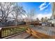 Backyard featuring a wooden deck, lush lawn, and mature trees at 1539 S Quail St, Denver, CO 80232