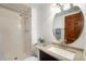 Bathroom featuring tile shower, vanity, and a round mirror at 1539 S Quail St, Denver, CO 80232