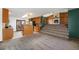 Inviting living room featuring a striking wood-paneled wall with a stone fireplace and adjacent kitchen at 1539 S Quail St, Denver, CO 80232