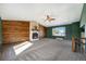 Spacious and inviting living room featuring a wood-paneled wall with a stone fireplace and bright sunlight at 1539 S Quail St, Denver, CO 80232