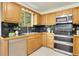 Traditional kitchen featuring stainless steel appliances, natural wood cabinets, and black tile countertops at 11333 Conifer Mountain Rd, Conifer, CO 80433