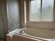 Bright bathroom featuring a white tiled tub surround and a large window providing natural light at 18336 E Amherst Dr, Aurora, CO 80013