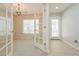Bright room with French doors and tile flooring, leading to a carpeted area with chandelier and large window at 9300 E Florida Ave # 1506, Denver, CO 80247
