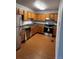 Well-lit kitchen featuring stainless steel appliances, wooden cabinetry, and dark countertops at 6396 S Hill St, Littleton, CO 80120