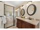 Bathroom featuring a tiled shower and double vanity sinks with updated fixtures at 673 Brentwood St, Lakewood, CO 80214