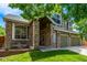 Inviting home exterior with beautiful stone columns, covered porch, well-maintained lawn, and mature trees at 1588 W 111Th Ave, Northglenn, CO 80234