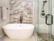 Stylish bathroom featuring a soaking tub, glass-enclosed shower with stone flooring, and elegant fixtures at 9045 E Floyd Ave, Denver, CO 80231