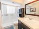 Bright bathroom featuring a glass-enclosed shower, vanity with sink, and decorative mirror at 9045 E Floyd Ave, Denver, CO 80231