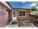 Close-up shot of the red brick house showcasing the front door and a window with trimmed bushes below at 5380 S Prescott St, Littleton, CO 80120