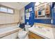 Bright bathroom with soaking tub, decorative mirror, and blue accent wall at 1069 Crestmoor Dr, Boulder, CO 80303