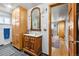 Bathroom showcasing wooden cabinets, vintage mirror, updated lighting, and view into another room at 1069 Crestmoor Dr, Boulder, CO 80303