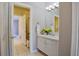 Bathroom featuring a sink with white cabinetry and a mirror with an adjacent room with a shower and tub at 6254 S Riviera Ct, Aurora, CO 80016