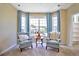 Bright sitting room with cozy armchairs, a round table, and a large bay window offering neighborhood views at 6254 S Riviera Ct, Aurora, CO 80016
