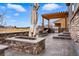 Outdoor space with a stone fire pit, grilling area, covered patio, and well-kept lawn at 745 Penstemon Dr, Henderson, CO 80640
