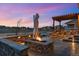 Outdoor space with a stone fire pit, grilling area, covered patio, and well-kept lawn at 745 Penstemon Dr, Henderson, CO 80640