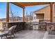 Outdoor kitchen with stainless steel grill, bar seating, and pergola covered seating area at 745 Penstemon Dr, Henderson, CO 80640