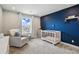 Cozy Bedroom with a white crib, comfortable chair, and a serene blue accent wall at 745 Penstemon Dr, Henderson, CO 80640