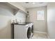 Practical laundry room equipped with washer, dryer, shelving, and convenient counter space at 745 Penstemon Dr, Henderson, CO 80640