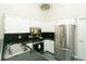 Well-lit kitchen featuring stainless steel appliances, black counters, and white cabinets at 9617 W Chatfield Ave # E, Littleton, CO 80128
