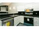Modern kitchen with stainless appliances, dishwasher, black tile backsplash, and white cabinetry at 9617 W Chatfield Ave # E, Littleton, CO 80128