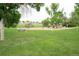 A community park with a playground, swings, and picnic tables under mature trees on a grassy field at 9617 W Chatfield Ave # E, Littleton, CO 80128