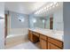 Bright bathroom featuring a dual sink vanity, soaking tub, and a separate glass-enclosed shower at 5596 S Urban St, Littleton, CO 80127