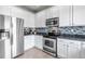 Contemporary kitchen featuring stainless steel appliances, tiled backsplash, and white cabinetry at 19593 E Hollow Creek Dr, Parker, CO 80134