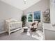Bright Bedroom featuring a crib, rocking chair, large windows, and plant near the window, creating a calming atmosphere at 6760 Mariposa Ct, Denver, CO 80221