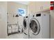 Functional laundry room with a modern washer and dryer, storage cabinets, and a clothing rack for convenience at 6760 Mariposa Ct, Denver, CO 80221