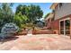 Back patio with stone paving, brick house, and landscaping featuring small garden and trees at 4660 E Briarwood Pl, Centennial, CO 80122