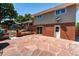Brick and siding home featuring a stone patio, lush greenery, and a white door at 4660 E Briarwood Pl, Centennial, CO 80122