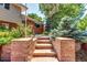Charming front entrance featuring stone steps, brick, and beautiful landscaping with mature trees at 4660 E Briarwood Pl, Centennial, CO 80122