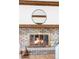 Close-up of a brick fireplace with a vintage brass firebox and wooden mantel at 6211 W Fremont Pl, Littleton, CO 80128