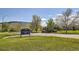 Community sign for Sunrise Ridge Park with grassy area and mature trees in the background at 6114 Salvia Ln, Arvada, CO 80403