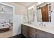 Bright bathroom with double vanity, stylish mirror, and a view into the connected bedroom at 11930 E Lake Cir, Greenwood Village, CO 80111