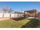 Fenced backyard features a pergola over a concrete patio, a grass lawn, and planter beds at 1556 Osceola St, Denver, CO 80204