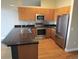 Kitchen featuring stainless steel appliances, a kitchen island, black countertops and light wood cabinets at 5401 S Park Terrace Ave # 204C, Greenwood Village, CO 80111