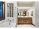 Bathroom featuring double sink vanity, large mirror and a tub with glass block window at 120 Windwood Cir, Breckenridge, CO 80424
