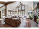 Bright living room with vaulted ceilings, wood beams, a stone fireplace, and large windows with wooded views at 120 Windwood Cir, Breckenridge, CO 80424
