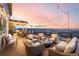 An outdoor deck with sofas, chairs, fire pit, and an outdoor dining table with sunset in the background at 1825 Wingfeather Ln, Castle Rock, CO 80108