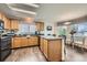 Well-lit kitchen with granite countertops, wood cabinets, black appliances, and a breakfast nook seating area at 4349 S Genoa Ct, Centennial, CO 80015