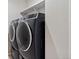 Modern laundry room with sleek black front-load washer and dryer, and upper shelf storage at 23883 E Minnow Cir, Aurora, CO 80016