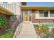Inviting front entrance featuring a charming wood door, brick accents, and well-maintained landscaping at 13934 W Warren Dr, Lakewood, CO 80228