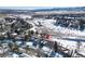 Aerial view of a house in a snowy neighborhood near a road and mountains at 12838 W Iliff Ave, Lakewood, CO 80228