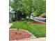 Landscaped front yard with green grass, mulch, and mature trees at 12838 W Iliff Ave, Lakewood, CO 80228