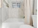 Bright bathroom showcases a tiled shower with tub and a window at 709 S Wolcott Ct, Denver, CO 80219